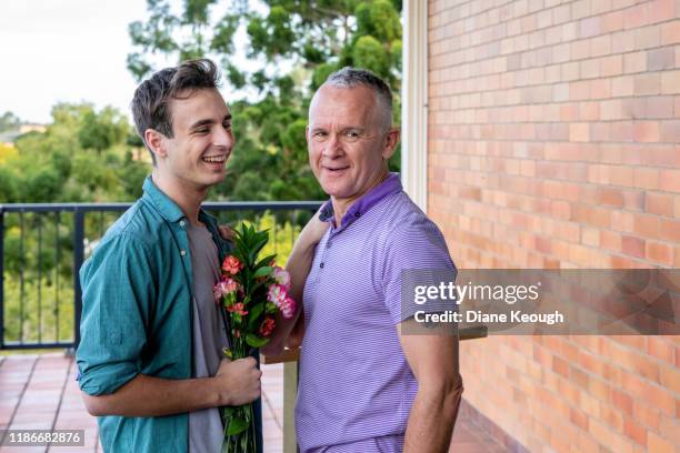 man giving his male partner flowers. - flowers australian stock pictures, royalty-free photos & images