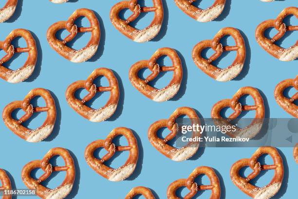 repeated pretzels on blue background - baviera fotografías e imágenes de stock