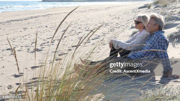 mature couple relax on beach at sunrise - early retirement stock pictures, royalty-free photos & images