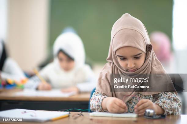 muslimischer grundschüler arbeitet an einem mint-projekt stockfoto - child scarf stock-fotos und bilder