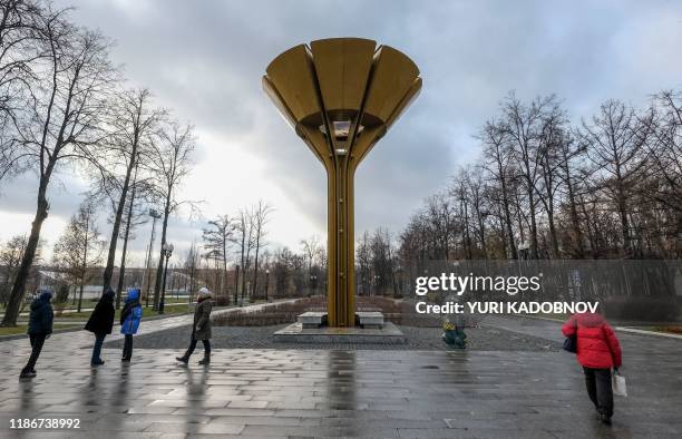 People walk past a sculpture of the mascot for the 1980 Moscow Olympics - Misha the bear - and the 1980 Summer Olympics Cauldron near the Luzhniki...