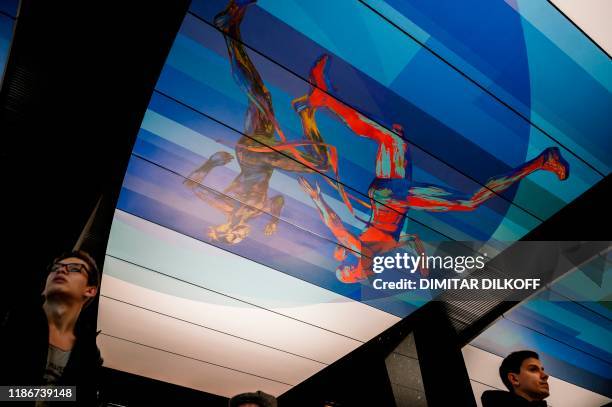 Commuters walk at CSKA /TSSKA/ metro station, with its ceiling decorated with images of runners, in Moscow on December 6, 2019. - The executive...