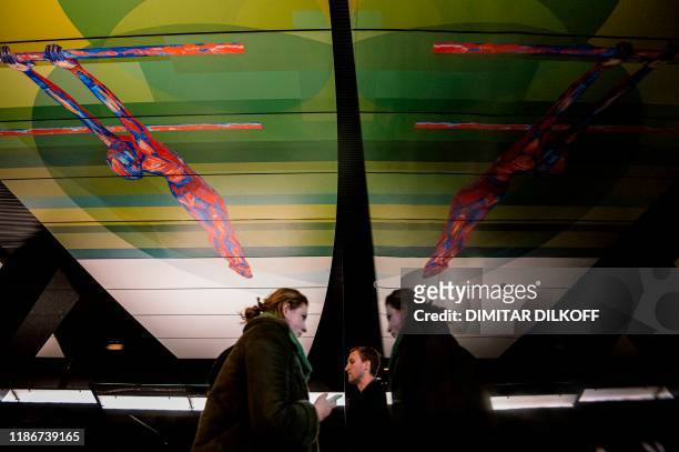 Commuters walk at CSKA /TSSKA/ metro station, with its ceiling decorated with an image of a gymnast, in Moscow on December 6, 2019. - The executive...