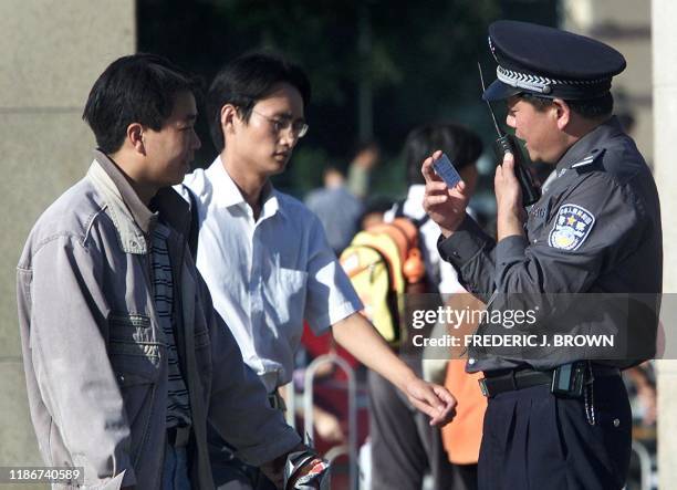 Policeman checks the identity card of a man at the Beijing railway station, 26 September 2001. As China gets ready for the week-long National Day...