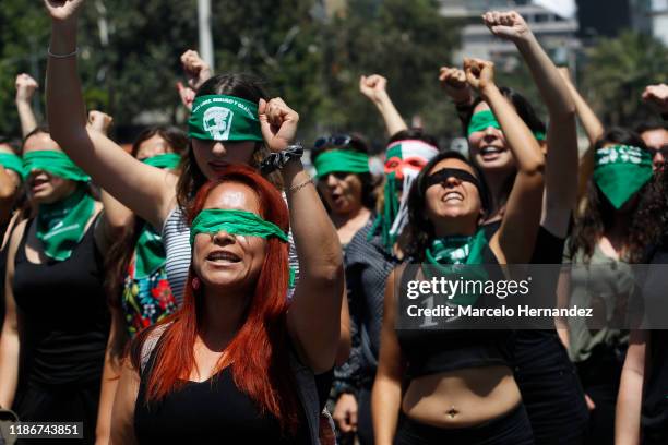 Demonstrators wearing green handkerchiefs covering their eyes sing and dance in a feminist flash mob performing "Rapist in Your Path" in protest of...