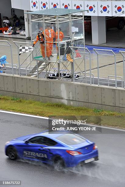 Track official waves the checkered flag as cars cross the line during an event to mark the 100-day countdown to the upcoming Korean Formula One Grand...