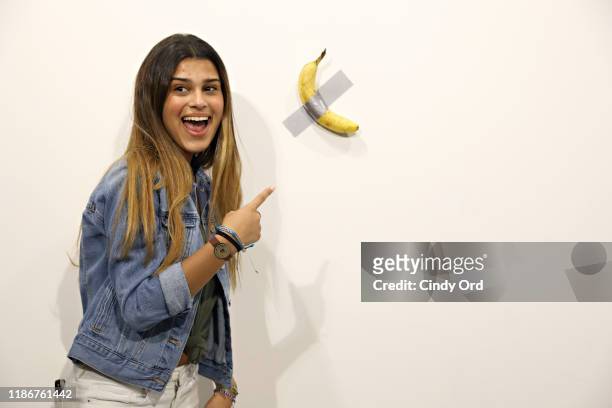 People post in front of Maurizio Cattelan's "Comedian" presented by Perrotin Gallery and on view at Art Basel Miami 2019 at Miami Beach Convention...