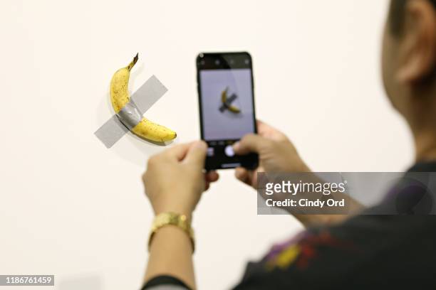 People post in front of Maurizio Cattelan's "Comedian" presented by Perrotin Gallery and on view at Art Basel Miami 2019 at Miami Beach Convention...