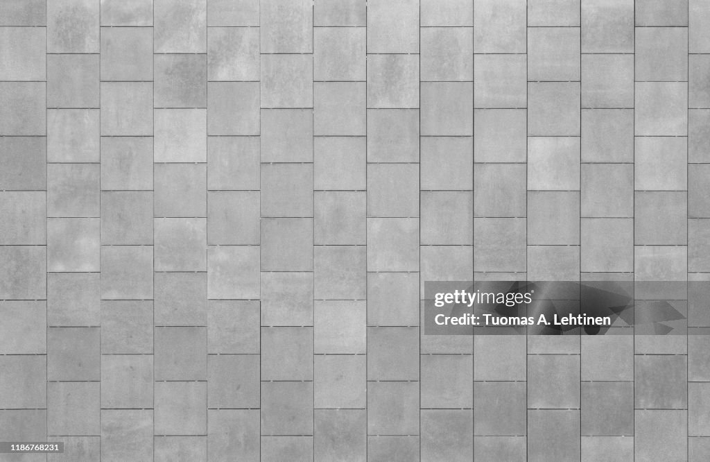 Front view of a wall made of rusty square shaped tiles or slabs. High resolution full frame textured background in black and white.