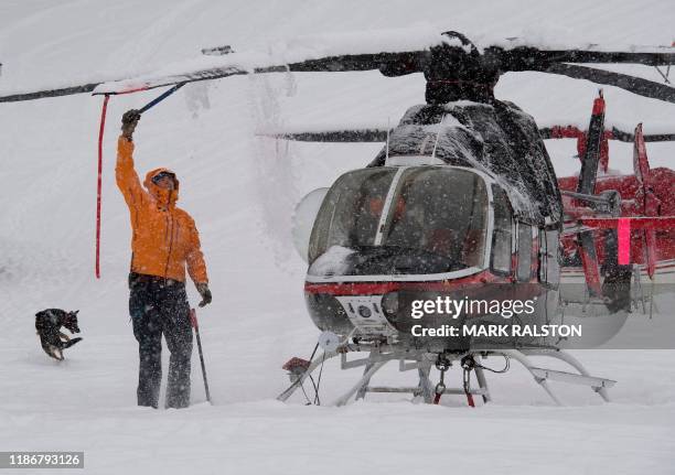 Rescue crews clear snow off a helicopter as heavy snow delays the start of the 1st Women's Downhill final at the Lake Louise ski resort in Alberta,...