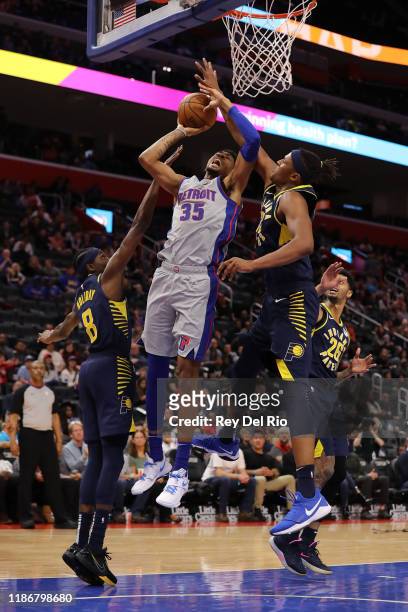 Christian Wood of the Detroit Pistons shoots between Justin Holiday and Myles Turner of the Indiana Pacers in the second quarter at Little Caesars...