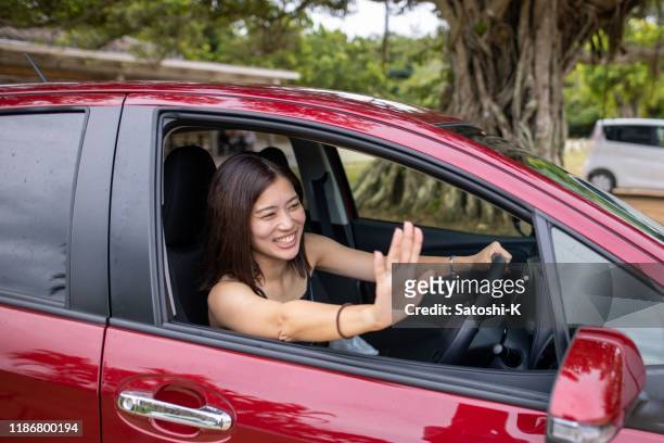 young woman in driver's seat waving hands - woman waving stock pictures, royalty-free photos & images