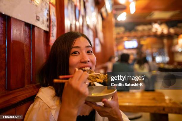 居酒屋で日本の「もずく天ぷら」を食べる若い女性 - restaurant night ストックフォトと画像