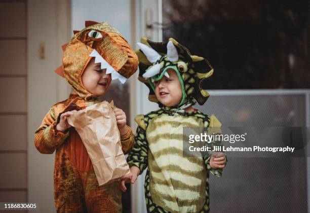 male twin toddlers dress up for halloween as dinosaurs - bühnenkostüm stock-fotos und bilder