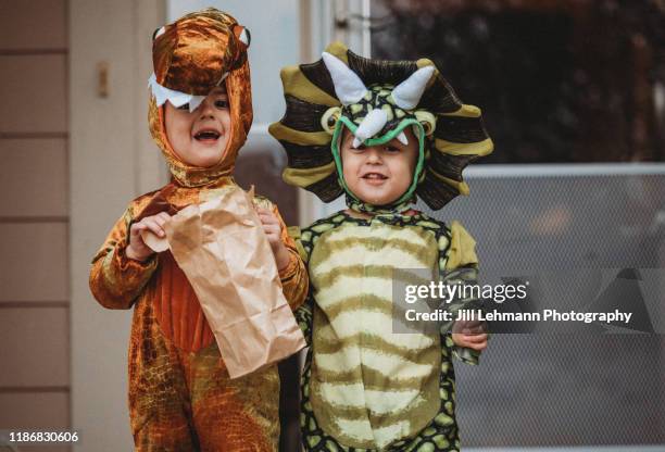 male twin toddlers dress up for halloween as dinosaurs - toneelkostuum stockfoto's en -beelden