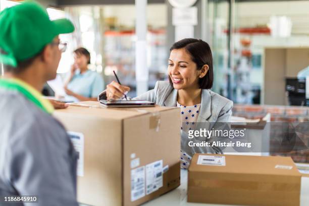 courier collecting or delivering parcels from small business - picking up mail stock pictures, royalty-free photos & images