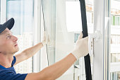 a specialist in installing plastic windows puts a double-glazed window in a window frame, close-up