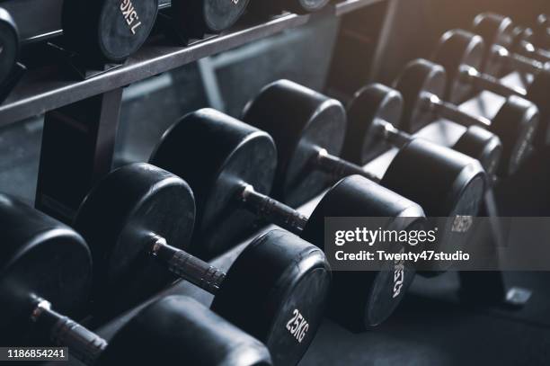 dumbbells on dumbbell rack. shallow focus, toned image - rack focus stock-fotos und bilder