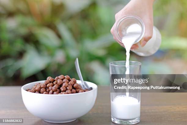 pouring milk into a glass with delicious chocolate cereals - chocolate milk splash stock pictures, royalty-free photos & images