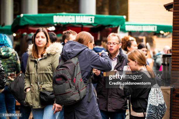 crowd of customers and tourists exploring and eating at borough market, london, uk - borough market stock pictures, royalty-free photos & images