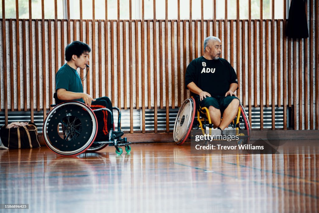 Men watching and officiating a wheelchair soccer game