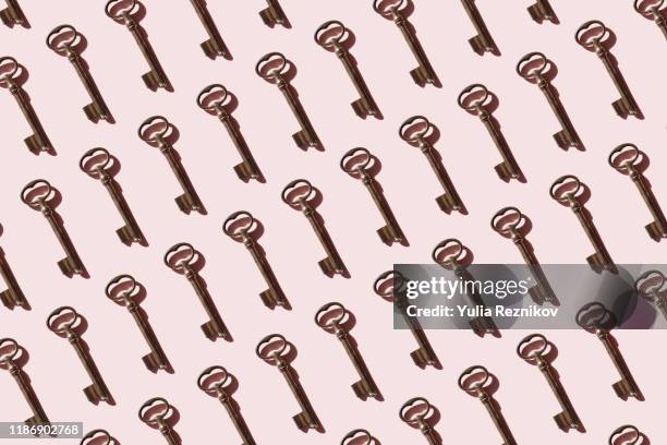 repeated old keys on pink background - key stock-fotos und bilder