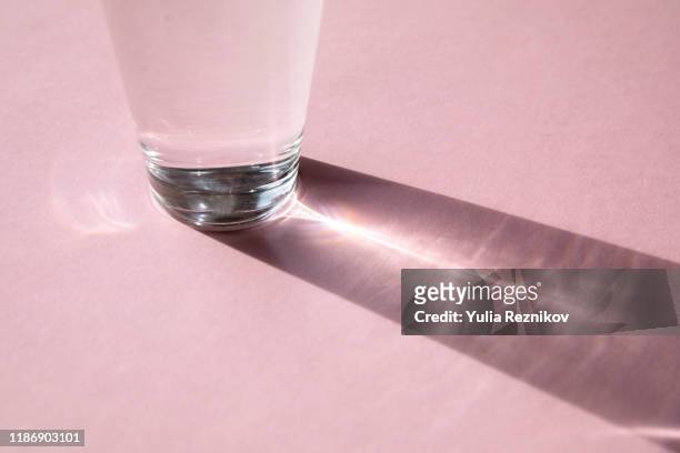 part of glass with water on the pink background - reflection photos et images de collection