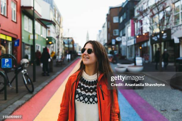 woman enjoying a wonderful day walking on the rainbow art reykjavik city center - reykjavik women stock pictures, royalty-free photos & images