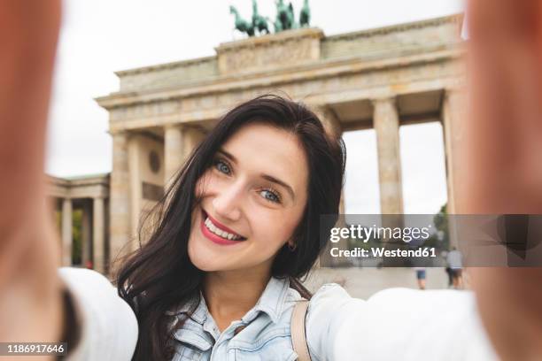 selfie of happy young woman at brandenburg gate, berlin, germany - brandenburg gate berlin stockfoto's en -beelden