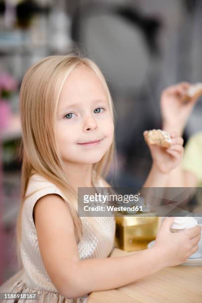 portrait of smiling little girl with gift box eating cookies - children only stock-fotos und bilder