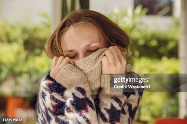 portrait of young woman with closed eyes sinking in her woolen sweater - woolly hat stock-fotos und bilder