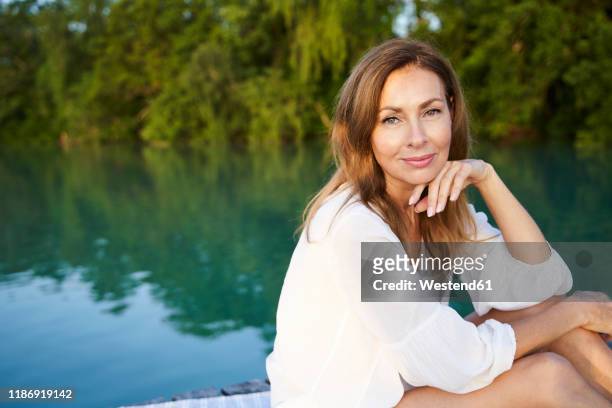 portrait of mature woman at a lake - older woman with brown hair stockfoto's en -beelden
