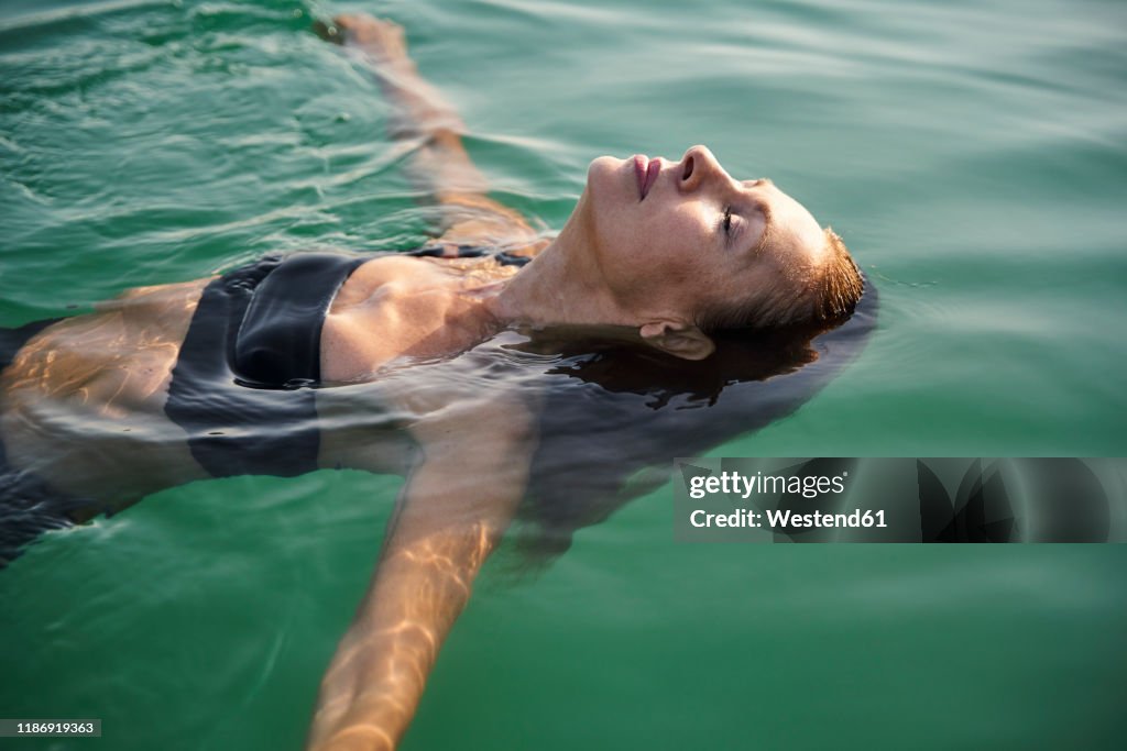 Mature woman floating in a lake with closed eyes