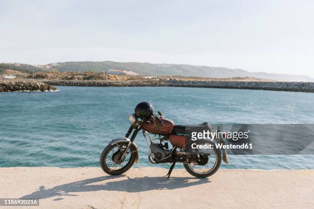 view of old motorcycle on the sea shore, nazare, portugal - mare moto foto e immagini stock