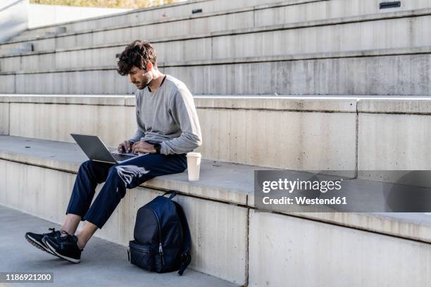 man sitting on outdoor stairs using laptop - italy city break stock pictures, royalty-free photos & images