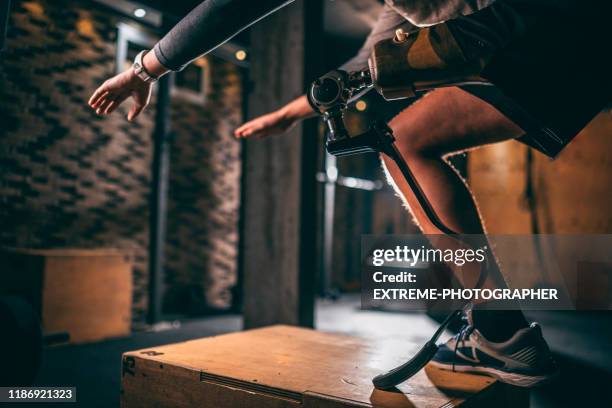 young athlete with a prosthetic leg doing step-ups in a sport arena in a gym - artificial limb stock pictures, royalty-free photos & images