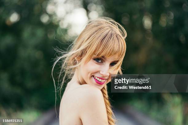 portrait of smiling blond young woman in nature - birthday suit stock-fotos und bilder
