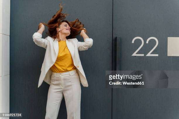 businesswoman in white pant suit, standing in front of entrance door - pant suit stockfoto's en -beelden