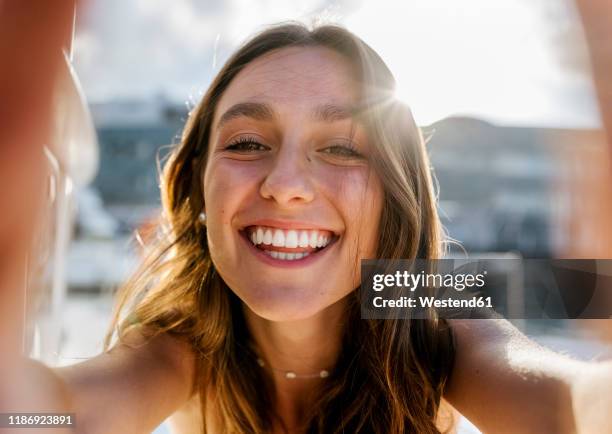 young beautiful woman taking a selfie on a sailboat - stralende lach stockfoto's en -beelden