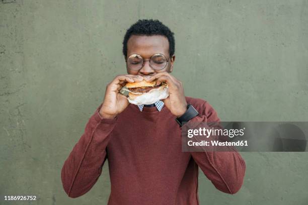 young man eating cheeseburger, with eyes closed - eating alone fotografías e imágenes de stock