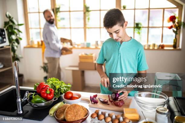 teenage boy cutting spanish onion in kitchen - cutting red onion stock pictures, royalty-free photos & images