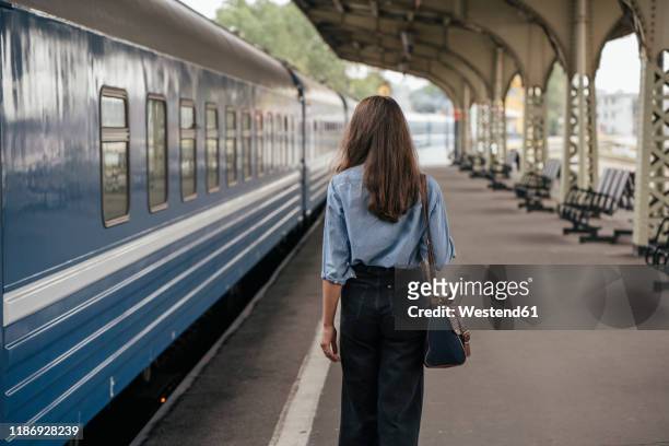 rear view of young female traveller walking on the platform - rückansicht stock-fotos und bilder
