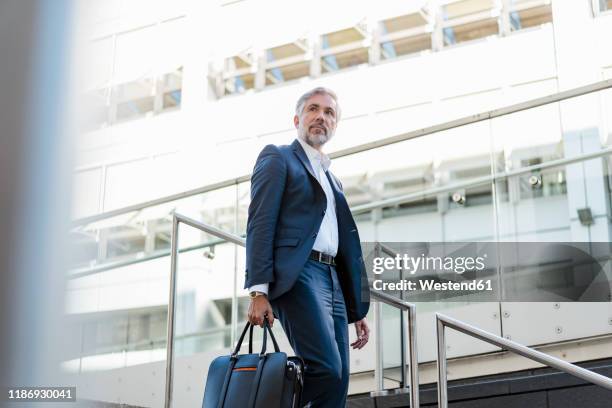 mature businessman holding bag walking down stairs in the city - portrait looking down stock pictures, royalty-free photos & images