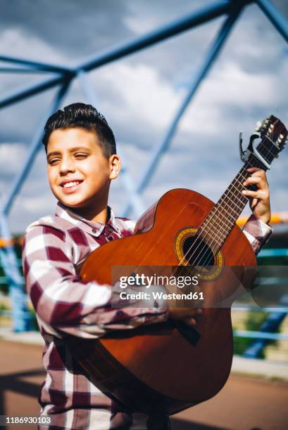 gypsy boy playing guitar on a bridge - pompadour fotografías e imágenes de stock