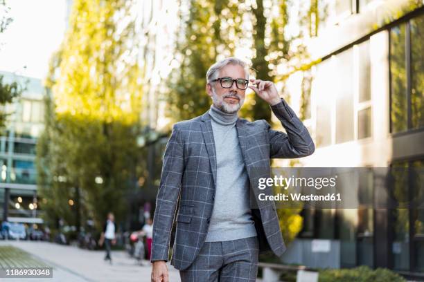 fashionable mature businessman on the go in the city - geblokt pak stockfoto's en -beelden