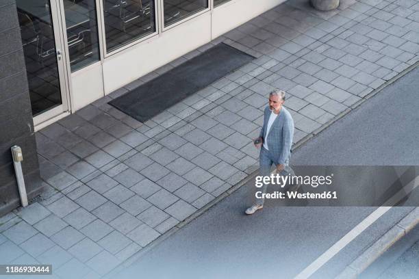 top view of mature businessman walking on a road - single lane road - fotografias e filmes do acervo