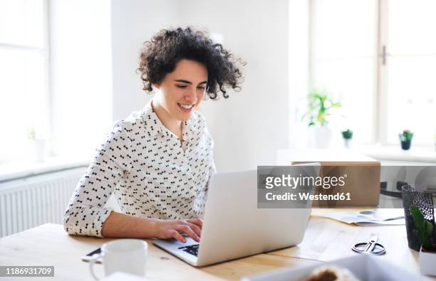 smiling young woman working on laptop at desk - trading desk photos et images de collection