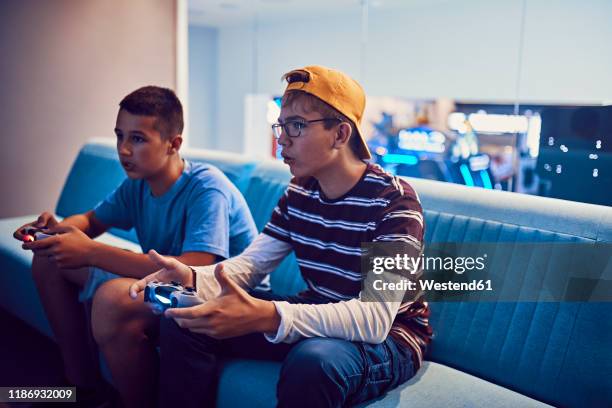 teenage friends playing video game in an amusement arcade - boys playing stock pictures, royalty-free photos & images