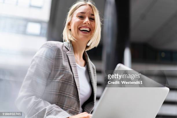 portrait of happy young businesswoman with laptop in the city - geblokt pak stockfoto's en -beelden