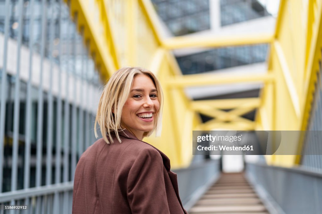 Portrait of happy young businesswoman on a bridge in the city